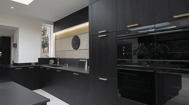 image of a luxurious kitchen design including black cabinets with gold accents and modern integrated appliances