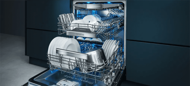 reduce your energy usage by only using your dishwasher when it is full. this image shows a fully integrated dishwasher open with plenty of dishes and cookware inside.