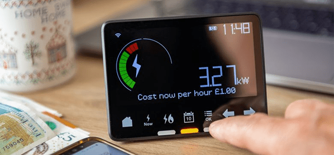 a great way to reduce your energy usage is to track your habits via a smart meter. this image displays a functioning smart meter in a home with a hand reaching put to control it.