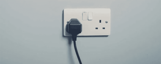 reduce your energy usage by turning off your non essental appliances i.e televisions and microwaves at the plug. this image shows a black cable plugged into a UK outlet with the switch turned on.