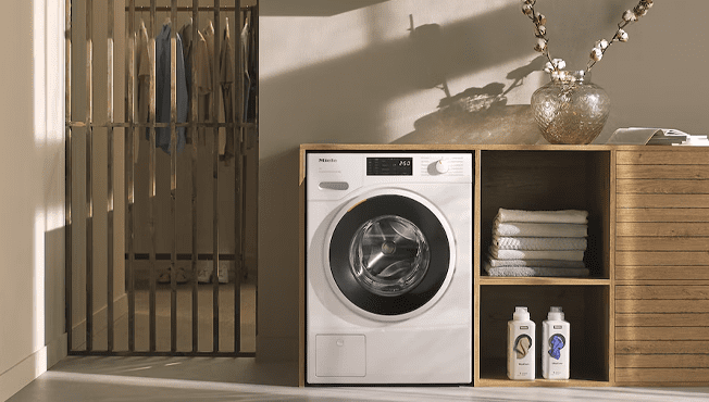 This image shows a Miele W1 washing machine in a neutral and modern utility room.