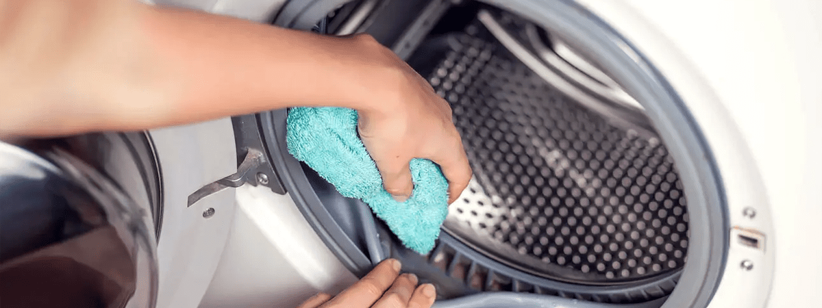 Someone cleaning the drum of a white washer dryer