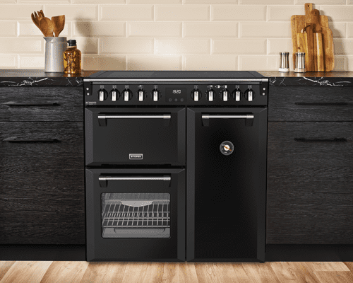 Room set image of a Stoves 90cm dual fuel range cooker in Black in a dark grey and cream kitchen.