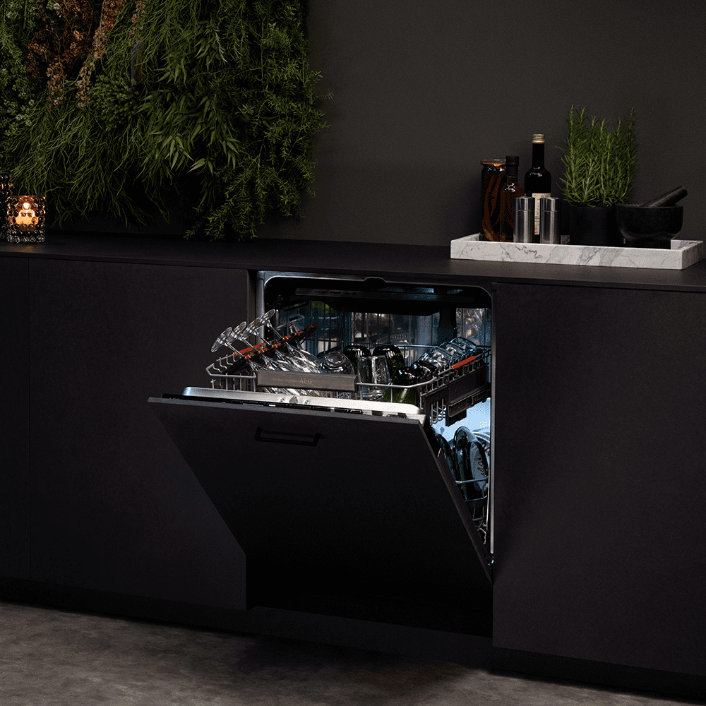 Image of an AEG fully integrated dishwasher in a black kitchen. The door of the dishwasher is slightly open showing clean pots and pans inside.