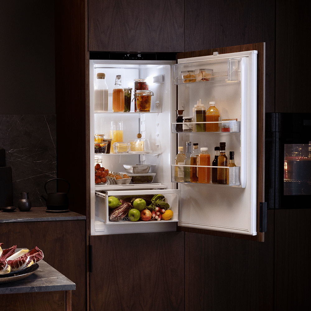 Close up of an integrated AEG fridge with the door open. Positioned in a dark wooden kitchen.