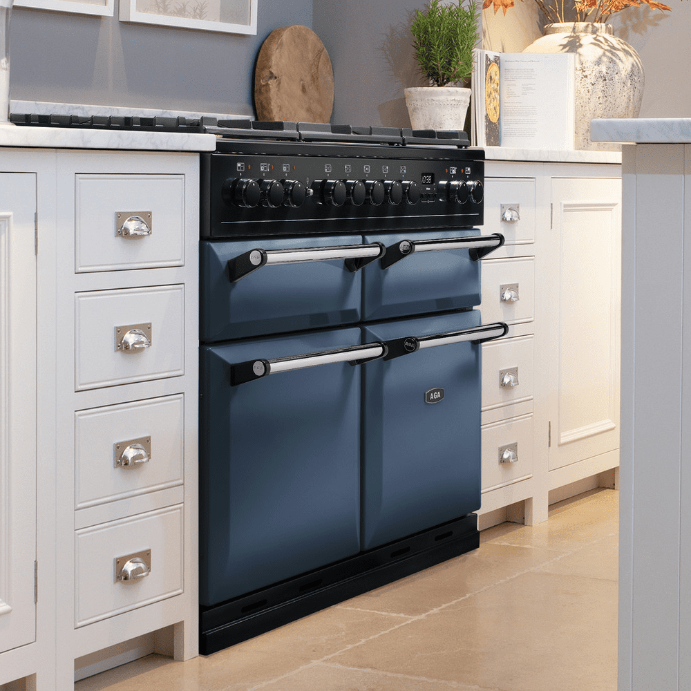 An AGA Rangemaster range cooker finished in Dartmouth Blue, in a white, farmhouse style kitchen.