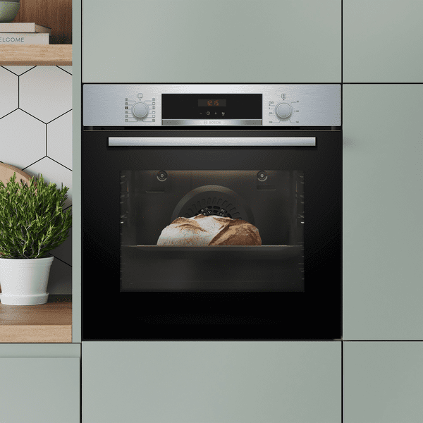 Close up of a Bosch built in single oven positioned in a mint green tall housing unit.