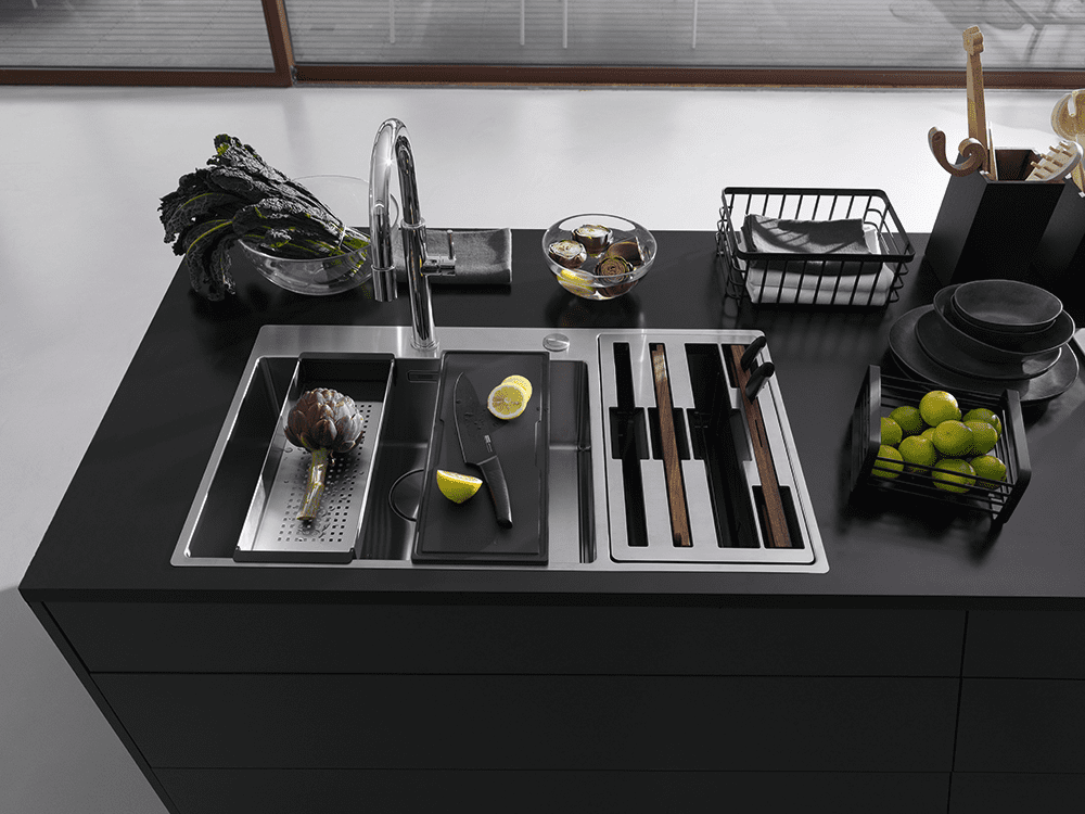 Image of the Franke Box Center Sink positioned on a black matte island. Featuring fresh green vegetables and a bowl of limes.