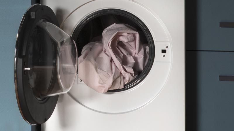 A white Haier washing machine with its door open. The drum is filled with laundry.
