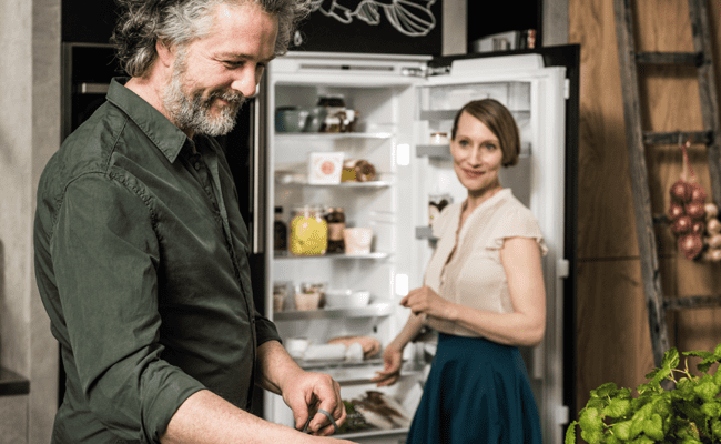 Couple standing in front of an open NEFF fridge.