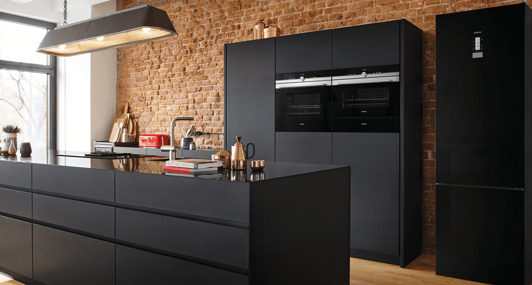 Large open plan kitchen with black cabinetry and exposed brick walls, featuring Siemens built in and freestanding appliances