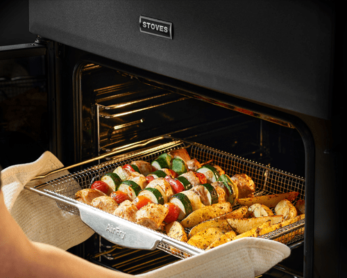 Close up of the Stoves range cooker air fry tray filled with brightly coloured vegetables and potato wedges.