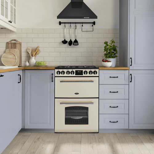 Image of a cream Belling mini range cooker positioned in a pale blue kitchen with a black chimney hood