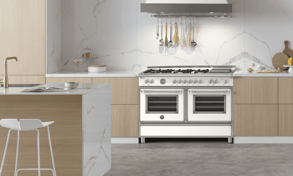 Image of a Bertazzoni Heritage range cooker finished in ivory, in a modern light wooden kitchen with a marble splashback.