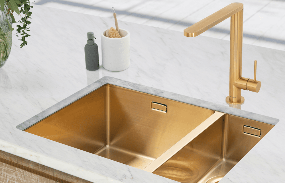 A kitchen worktop featuring an undermount Caple Mode sink finished in gold with a matching gold tap.