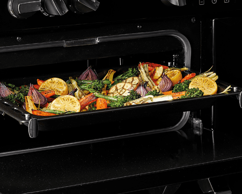 Close up of the conventional oven and Maxi Grill feature on a Stoves range cooker. There is a variety of brightly coloured vegetables roasting in the pan.