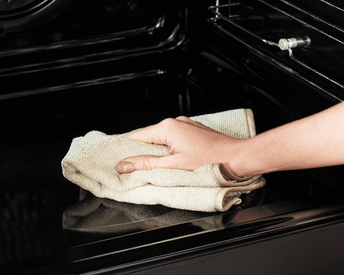 Close up of someone cleaning the interior of a Belling range cooker with a microfibre cloth