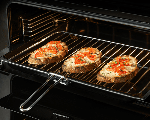 Close up of the Belling range cooker separate grill feature. There are three slices of cheese and tomatoes on toast cooking under the grill.