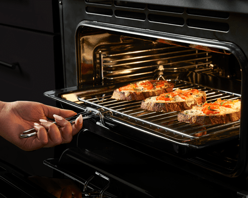 Close up image of a Stoves range cooker, using the grill pan to cook cheese and tomatoes on toast