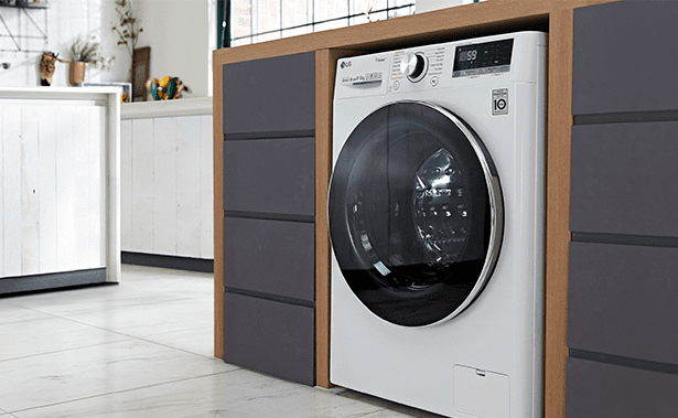Close up of an LG washing machine in white, positioned in a grey and white kitchen