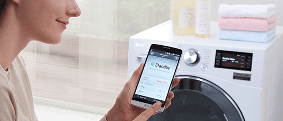 Close up of woman using her smart phone to activate her LG washing machine