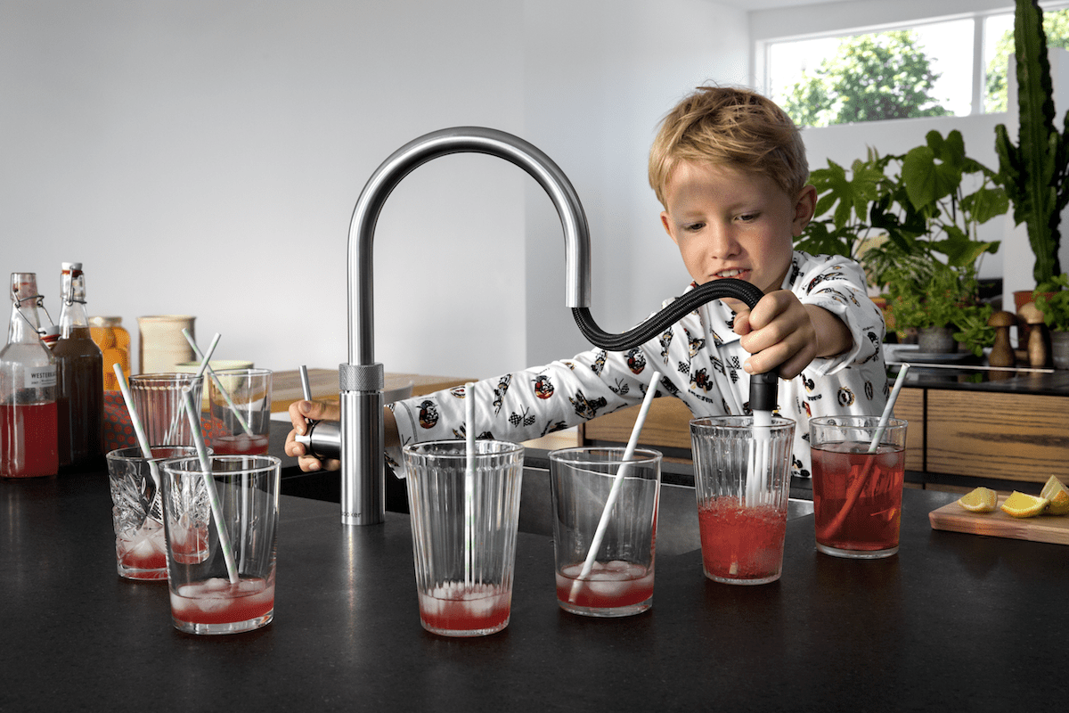 Image of a young boy pouring cold water into several glasses of cordial using the Quooker Flex tap.
