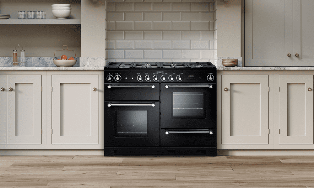 A dual fuel Rangemaster Kitchener range cooker in black in a cream shaker style kitchen