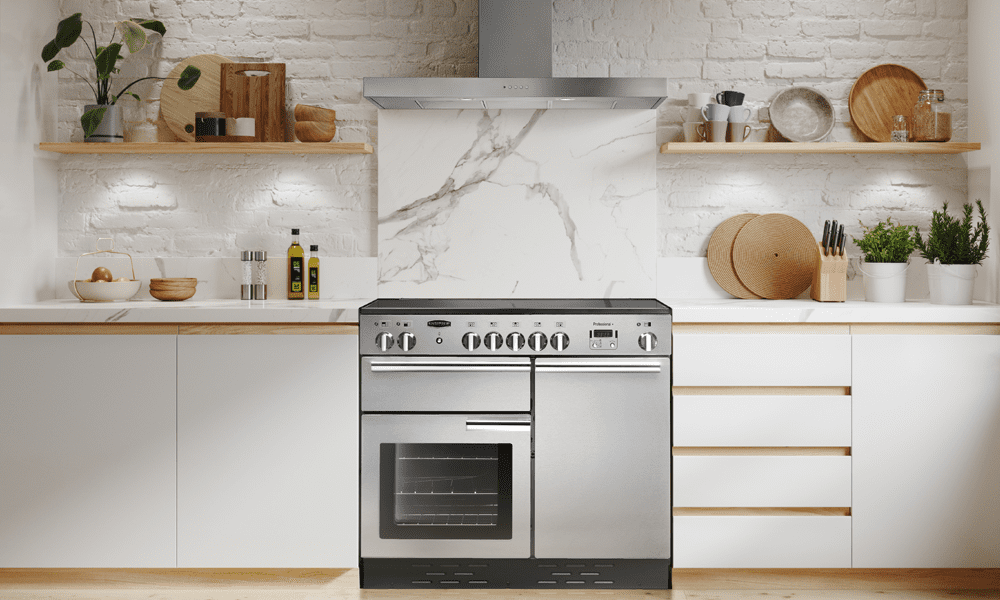 A Rangemaster Professional range cooker in stainless steel. Featured in a white kitchen with a marble splashback and stainless steel Rangemaster flat chimney hood.