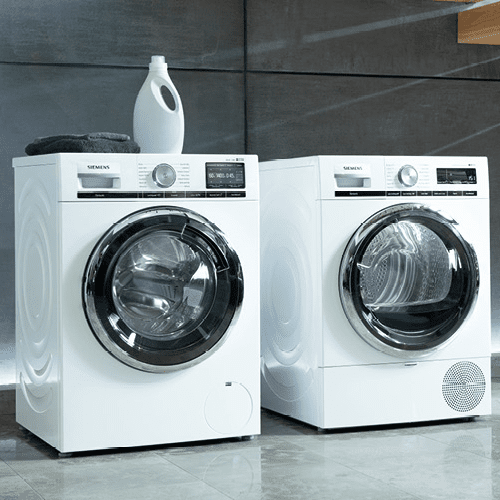 Image of a Siemens washing machine and tumble dryer sat alongside each other in a grey and white utility room.