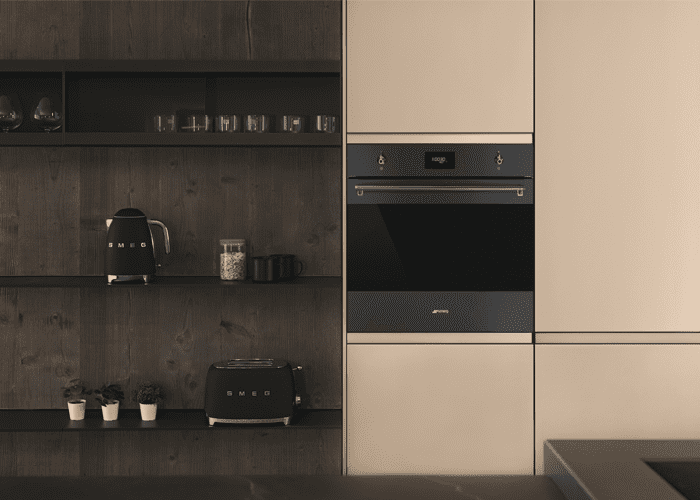 A Smeg Classic built in oven in a tall housing unit in a modern beige and brown kitchen.