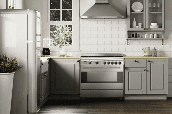 Kitchen featuring a Smeg Concert range cooker in stainless steel with the matching chimney hood, in a sage green and white.