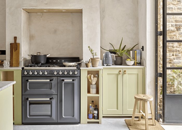 Image of a Smeg Victoria range cooker in grey, positioned in a pale green and limestone washed kitchen.