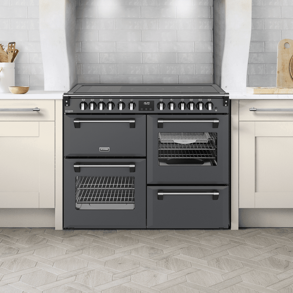 Close up image of a grey induction Stoves range cooker in a white and wooden kitchen with cream cabinets