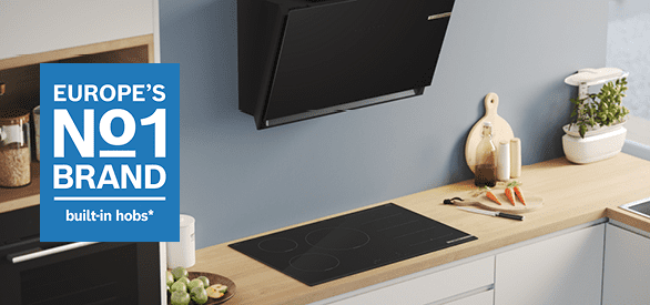 Image of a Bosch induction hob and angled chimney hood in a modern white and wooden kitchen with blue walls. There is a text box which says 'Europe's No.1 brand for built in hobs'