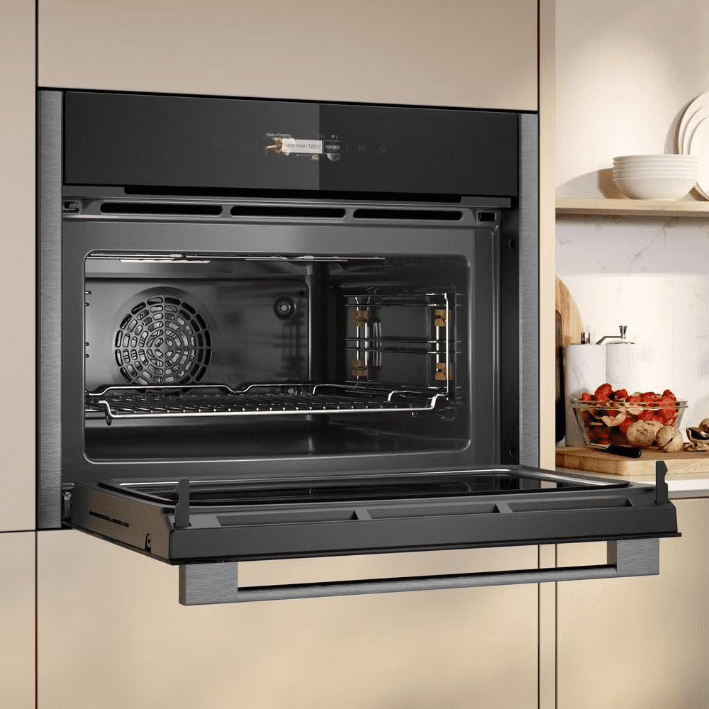Close up of a NEFF combination microwave installed into a tall housing unit. The microwave door is open fully to show the spacious interior.