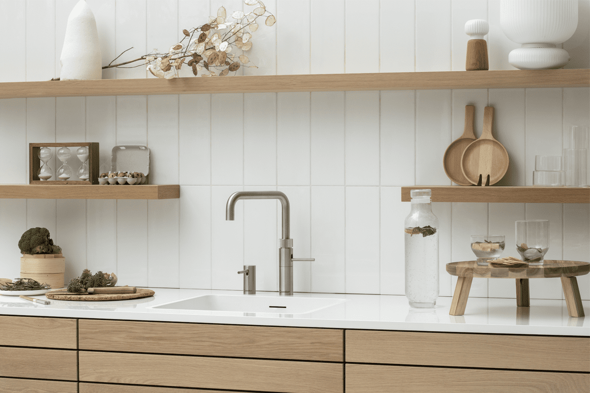 Lifestyle image of a Quooker Fusion boiling water tap in stainless steel, fitted in a white and wooden kitchen