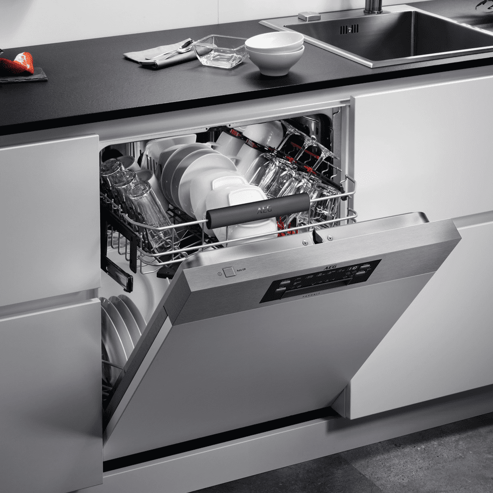 A close up of an AEG semi integrated dishwasher with the door slightly ajar showing clean dishes inside