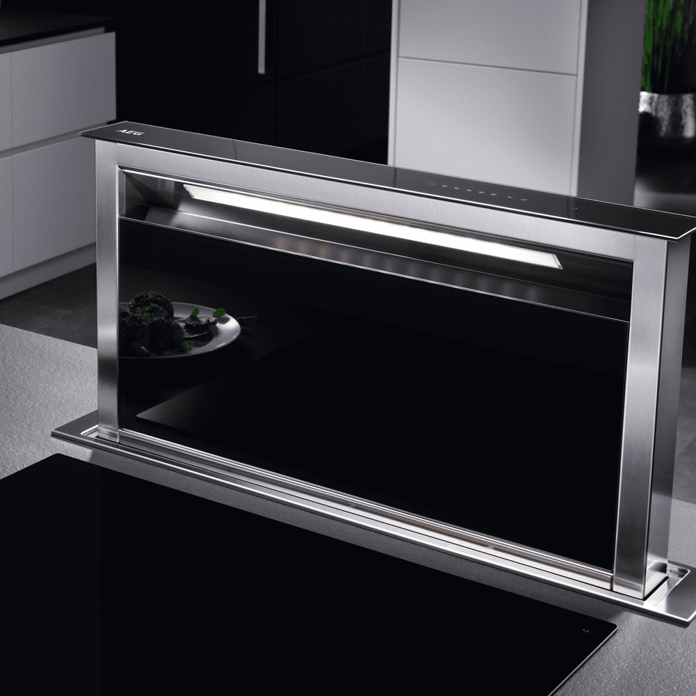 Close up of an AEG downdraft hood in a black and silver kitchen