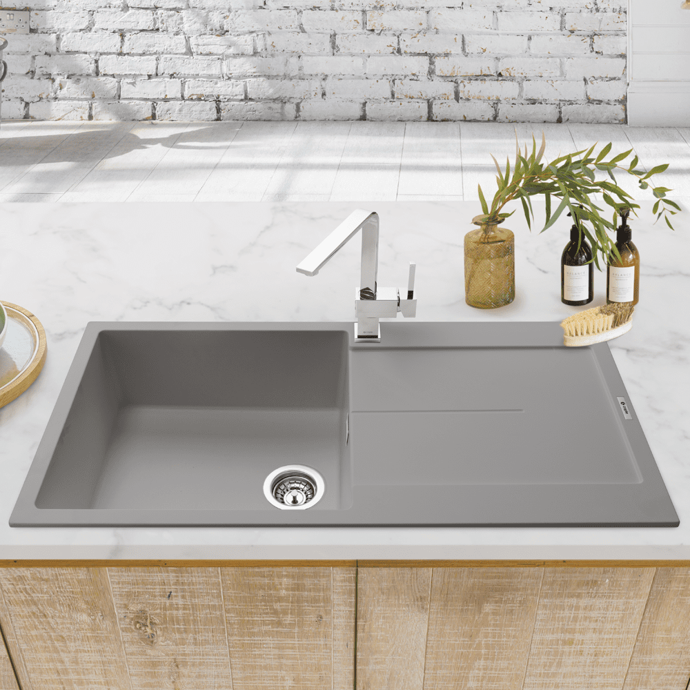 Image of a fragranite grey inset sink on a white countertop with wooden cabinetry.