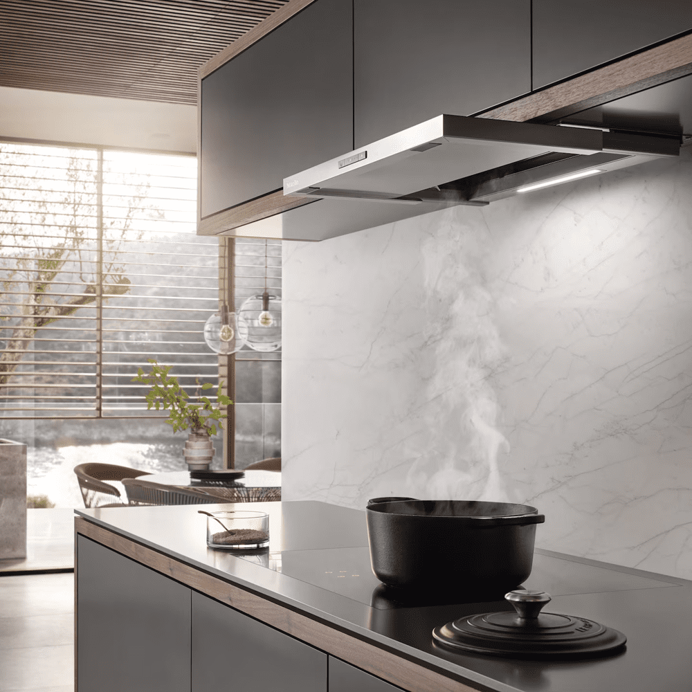 Image of a Miele telescopic hood in a large, open plan kitchen. A pan is boiling below the hood, extracting the steam into the cooker hood.